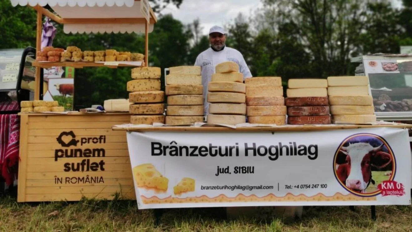 Stand cu brânzeturi artizanale la târg, cu produse variate și un producător zâmbitor.