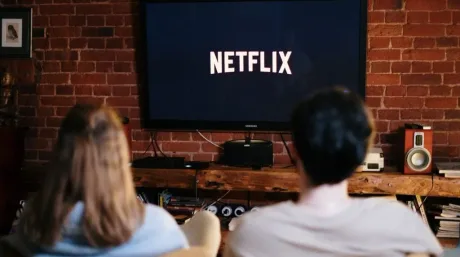 Oameni care vizionează Netflix pe un televizor în living.