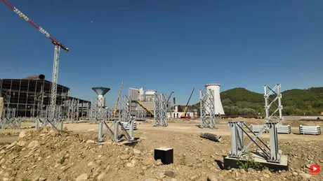 Lucrări de construcție la combinatul siderurgic Oțelu Roșu, cu echipamente moderne în fundal.