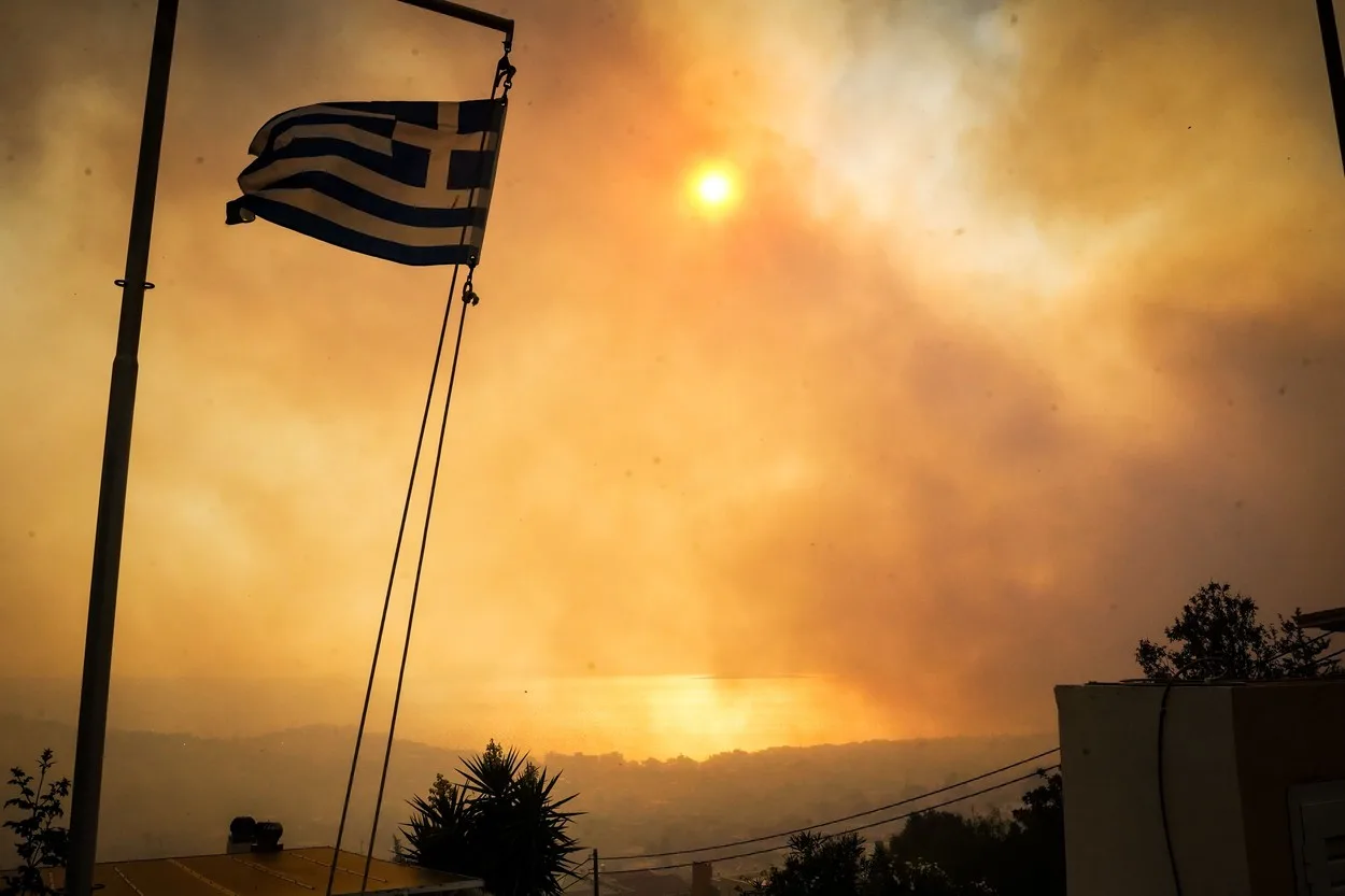 Incendii de vegetație în Grecia, cu soarele acoperit de fum.