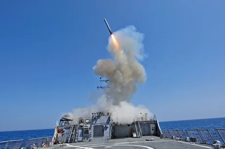 Lansare de rachetă Tomahawk de pe un vas militar pe fundalul cerului albastru.