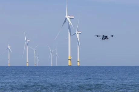 Turbine eoliene pe fundalul mării, cu un dronă în zbor.