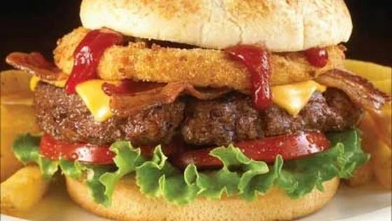 Burger cu carne, brânză, salată și sos, servit cu cartofi prăjiți.