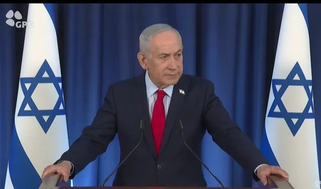 Benjamin Netanyahu susținând o declarație în fața drapelului israelian.