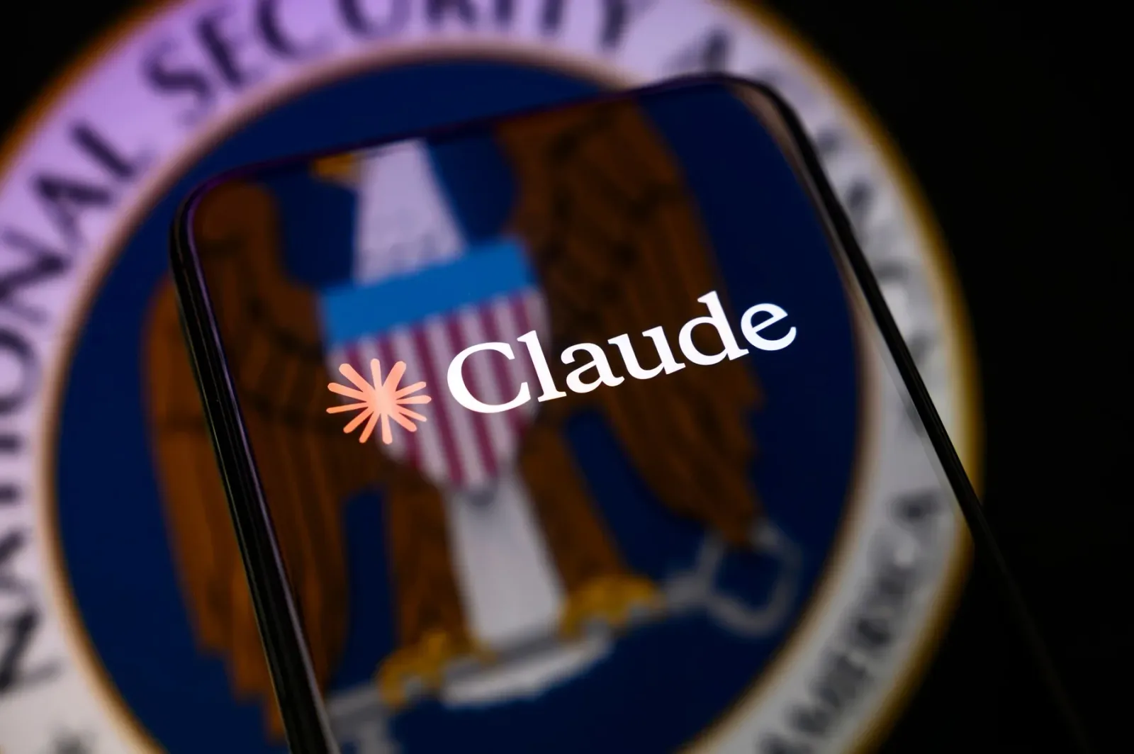 Logo-ul Claude pe un fundal cu simbolul securității naționale americane.