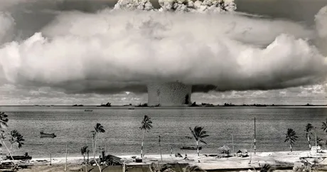 Explozie nucleară sub un nor de fum pe fundalul mării.