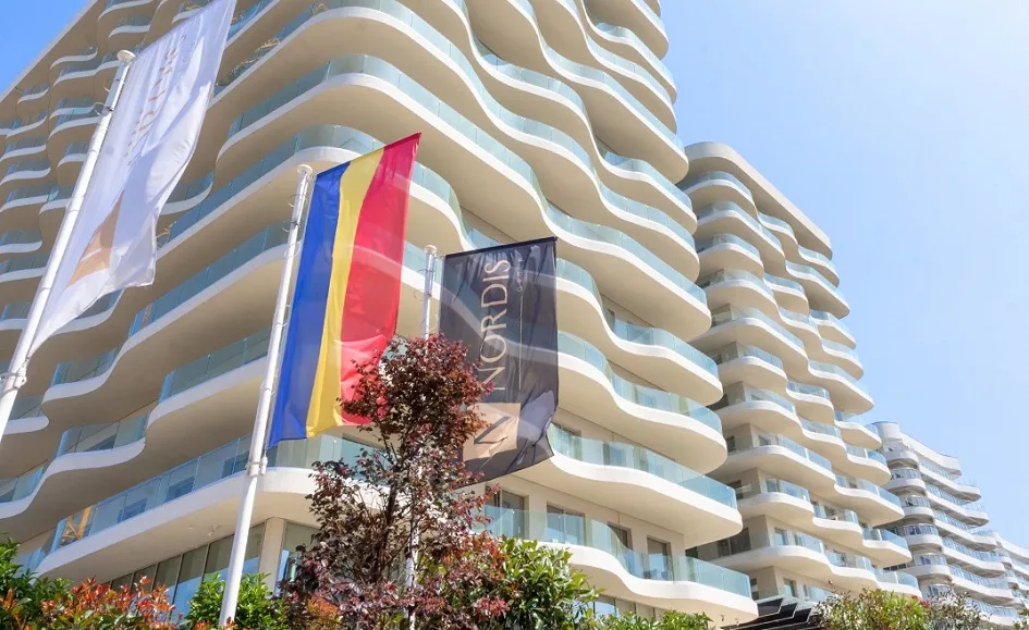 Clădiri moderne cu steaguri fluturând în față, simbolizând un proiect imobiliar.