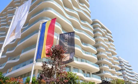 Clădiri moderne cu steaguri fluturând în față, simbolizând un proiect imobiliar.