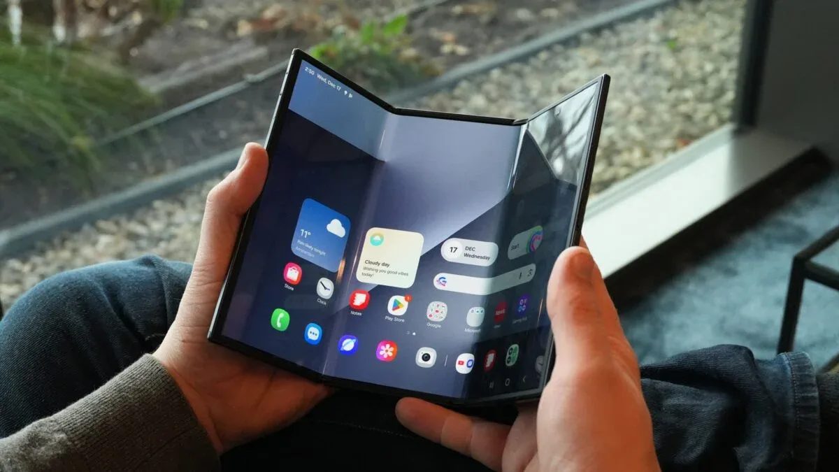 Un telefon pliabil Galaxy Z TriFold în mână, cu ecran deschis.