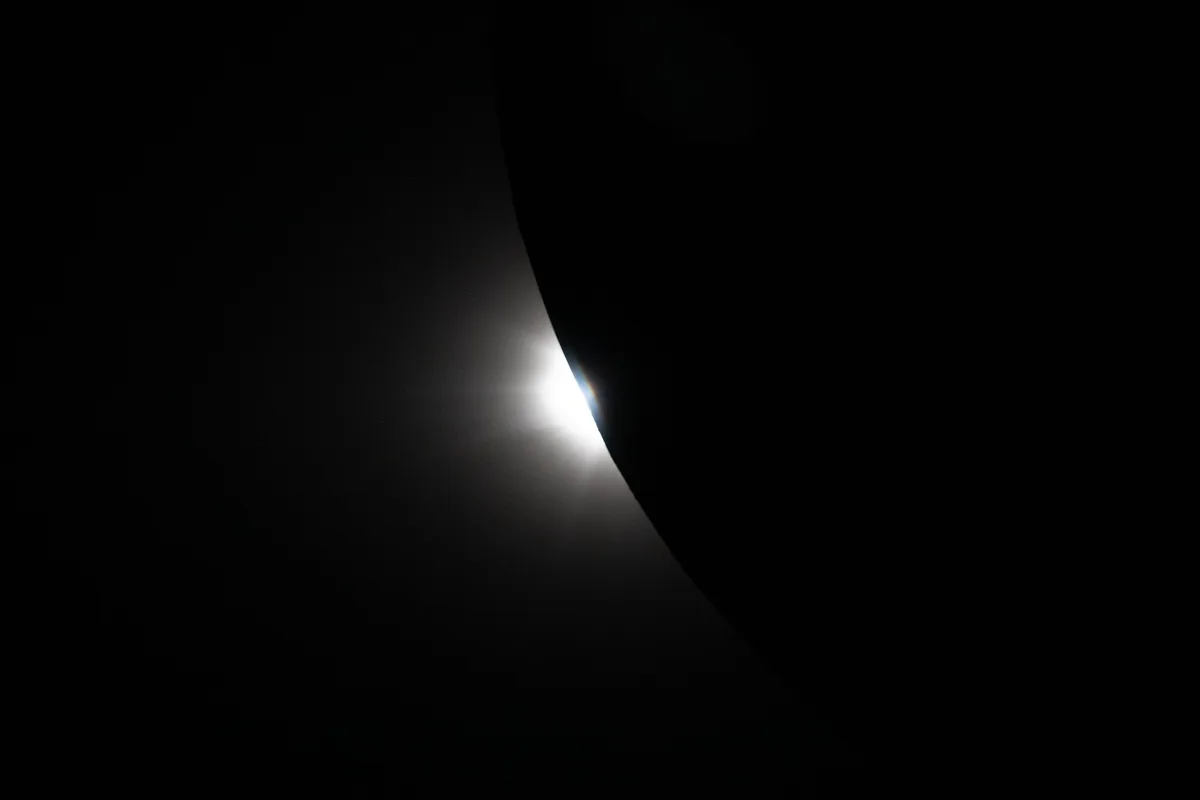 Coroana solară vizibilă în timpul eclipsei, cu Luna în prim-plan.