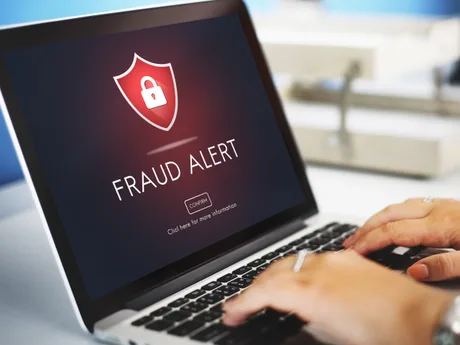 Laptop cu mesaj de alertă pentru fraudă pe ecran.