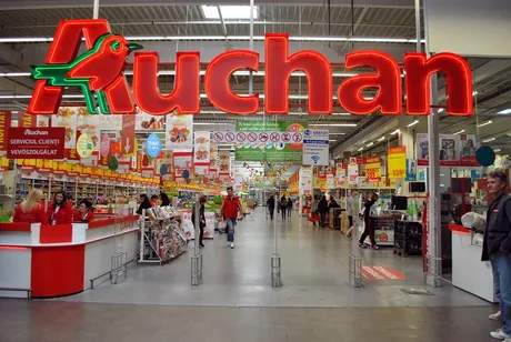Interiorul unui magazin Auchan, plin de produse și clienți activi.