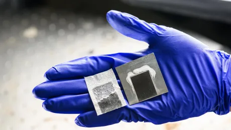 Sistem de desalinizare solară cu panouri din metal negru, prezentat pe o mână.