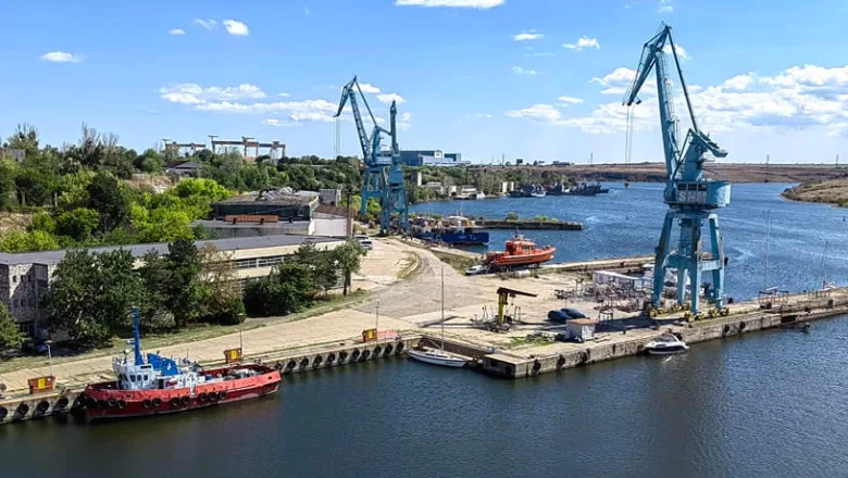 Vedere panoramică a Șantierului Naval Damen Mangalia, cu macarale și ambarcațiuni pe apă.