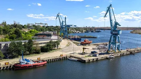 Vedere panoramică a Șantierului Naval Damen Mangalia, cu macarale și ambarcațiuni pe apă.