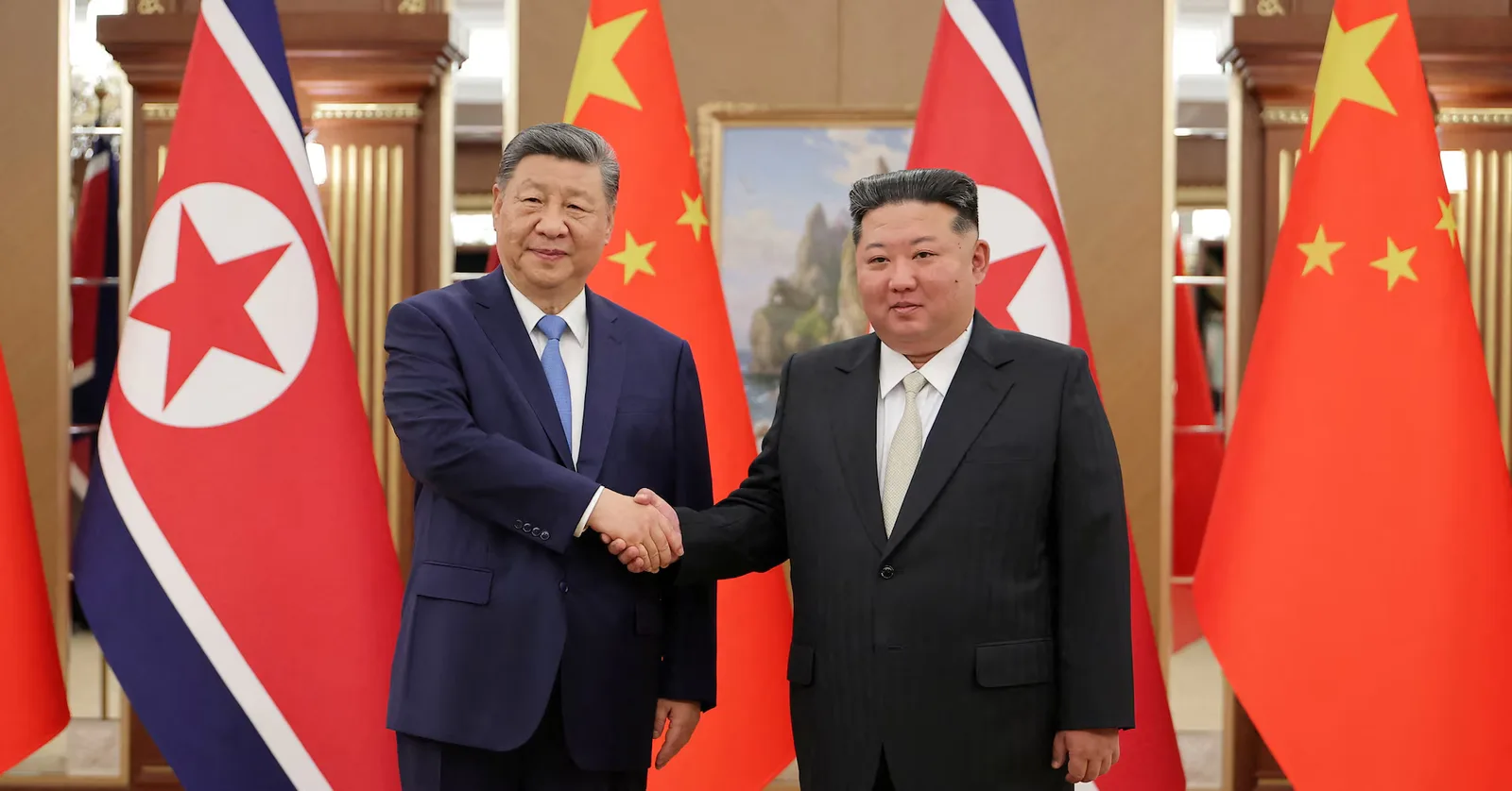Xi Jinping și Kim Jong Un se salută în fața steagurilor naționale.