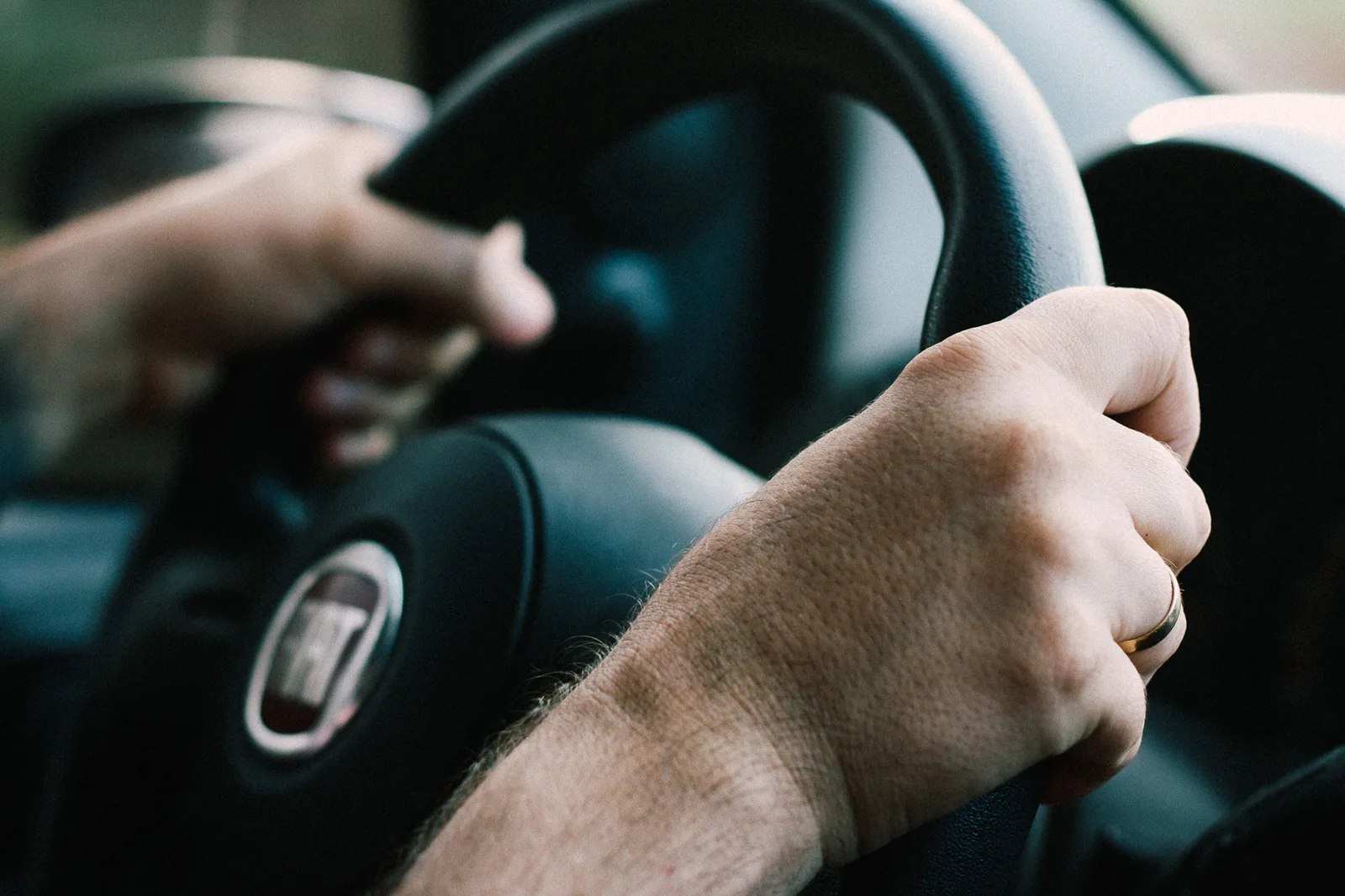 Mâini care țin volanul unei mașini, simbolizând conducerea auto.