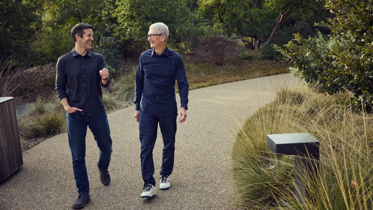 John Ternus și Tim Cook discutând în Apple Park, înconjurați de natură.