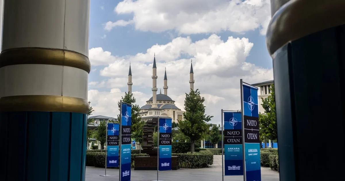 Bannere NATO în Ankara, cu moscheea în fundal, sub un cer senin.