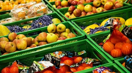 Legume și fructe expuse în coșuri verzi la supermarket.