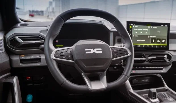 Interior modern al unui vehicul Dacia, cu volan și display digital.