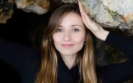 Cercetătoare cu zâmbet, înconjurată de stânci, simbolizând inovația în AI.