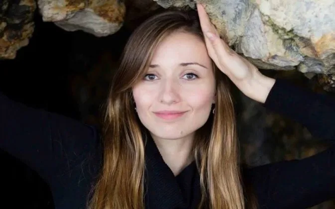 Cercetătoare cu zâmbet, înconjurată de stânci, simbolizând inovația în AI.