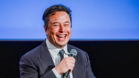 Elon Musk zâmbind în timpul unui discurs despre tehnologie și inovație.