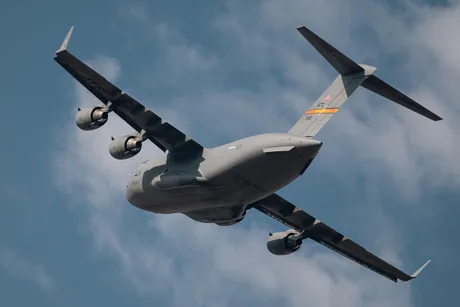 Avion militar C-17 Globemaster zburând pe un fundal de cer albastru.