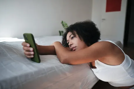 Tânără privind telefonul, reflectând asupra dificultăților de angajare.