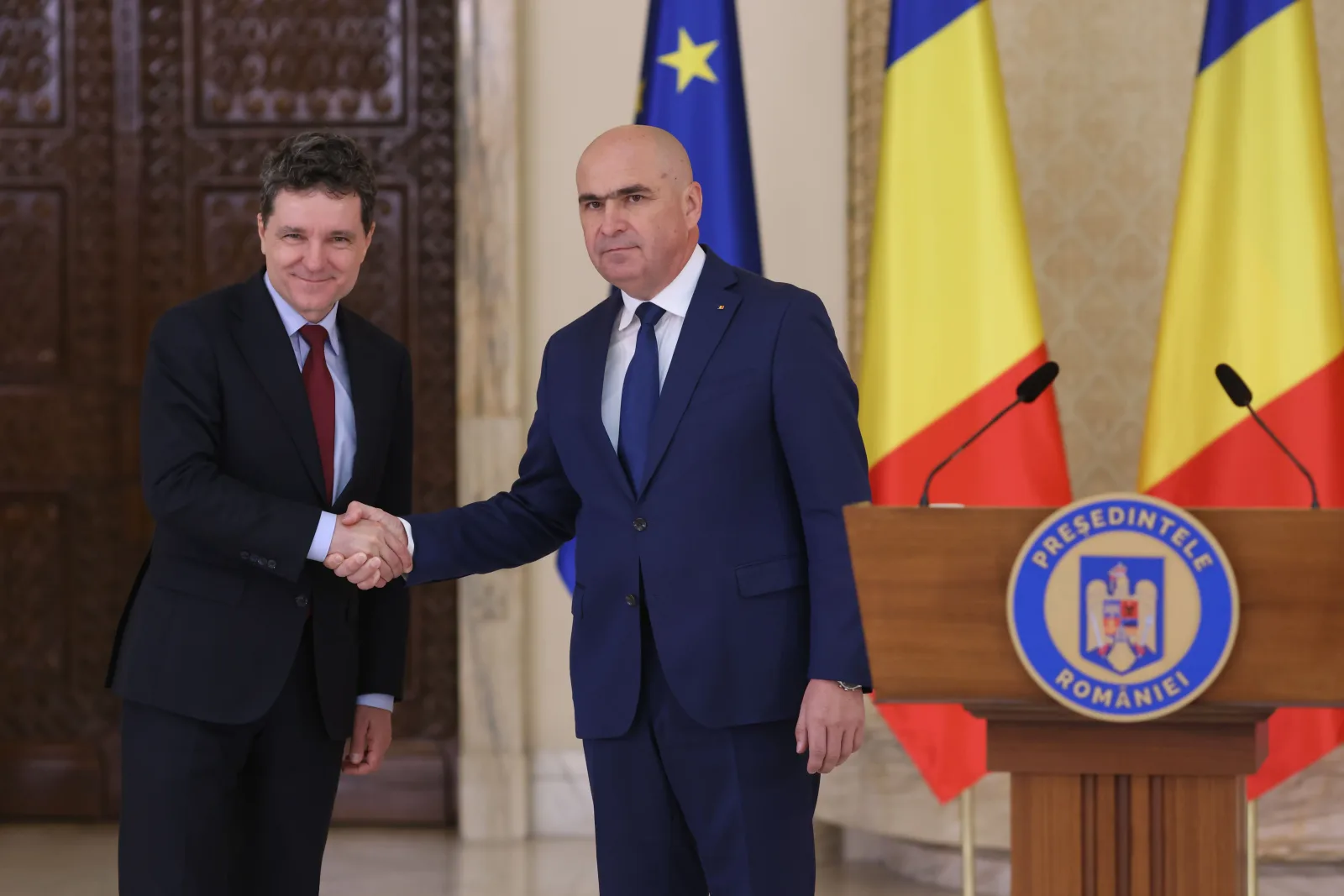 Ilie Bolojan și Nicușor Dan se salută într-un cadru oficial.
