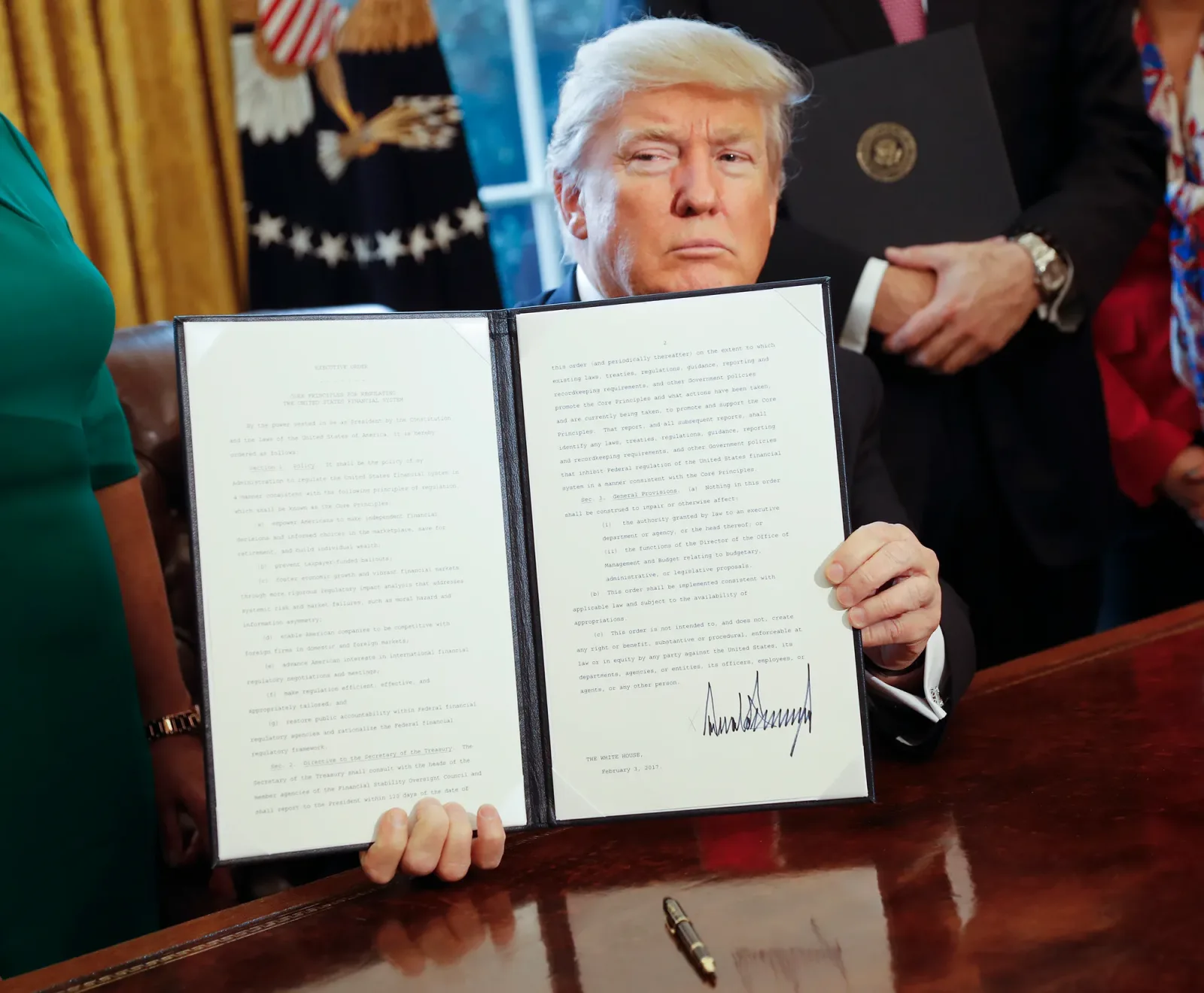 Donald Trump prezintă un document semnat în birou.