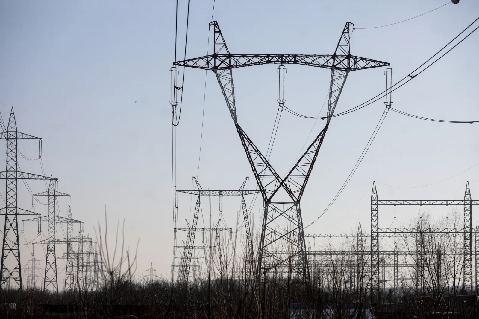Stâlpi de înaltă tensiune într-un peisaj urban, simbolizând rețeaua electrică.