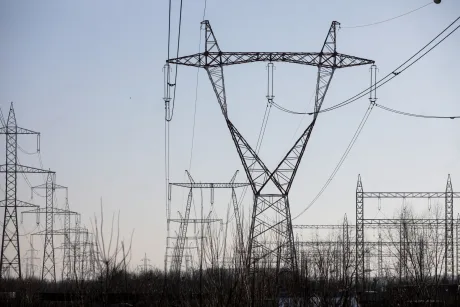 Stâlpi de înaltă tensiune într-un peisaj urban, simbolizând rețeaua electrică.
