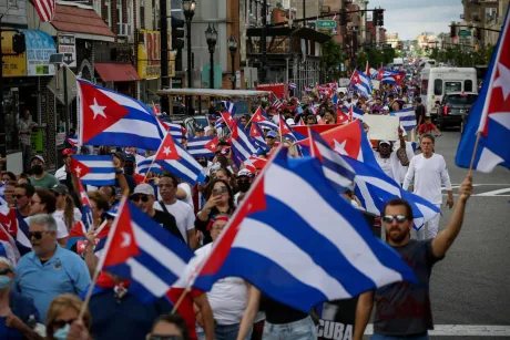 Protest cu steaguri cubaneze pe străzile unei localități aglomerate.