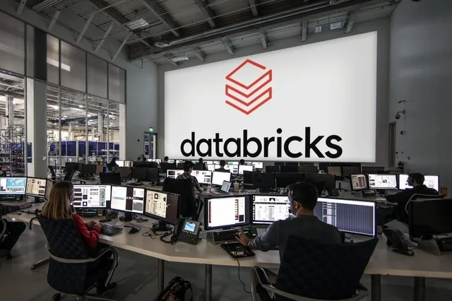 Birou modern cu echipamente tehnologice avansate și logo-ul Databricks pe un ecran mare.