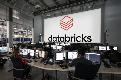 Birou modern cu echipamente tehnologice avansate și logo-ul Databricks pe un ecran mare.