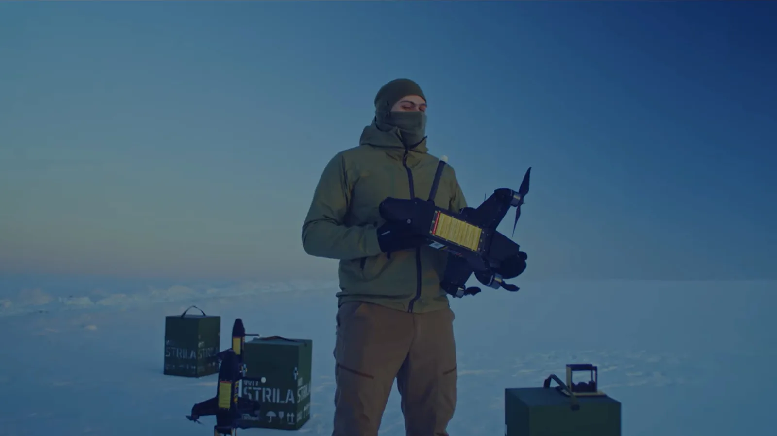 Un bărbat ține o dronă Strilla într-un peisaj de iarnă.