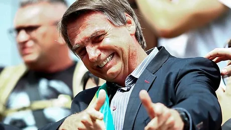 Jair Bolsonaro zâmbește și face semne de aprobat în timpul alegerilor.