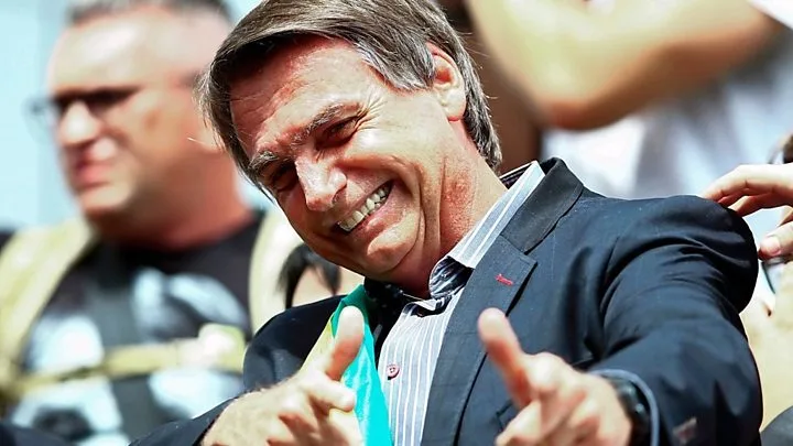 Jair Bolsonaro zâmbește și face semne de aprobat în timpul alegerilor.