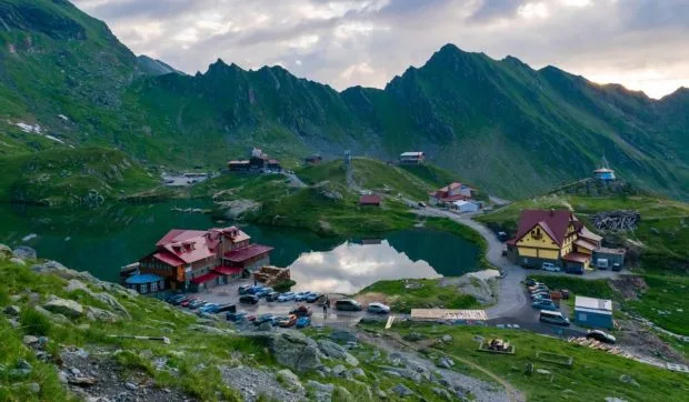 Peisaj montan cu pensiuni și lac în Munții Făgăraș, ideal pentru ecoturism.