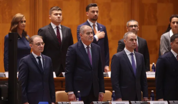 Reuniune oficială cu participanți în fața unui panou de prezentare.