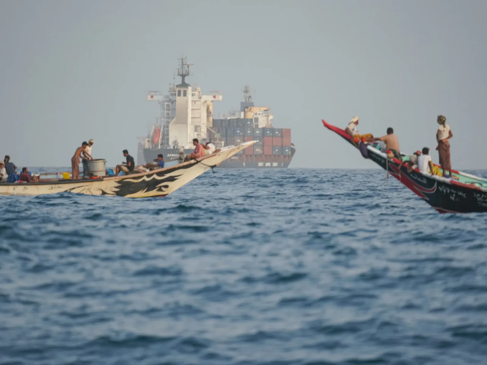 Bărci de pescuit navigând în apropierea unui vas de marfă pe Marea Roșie.