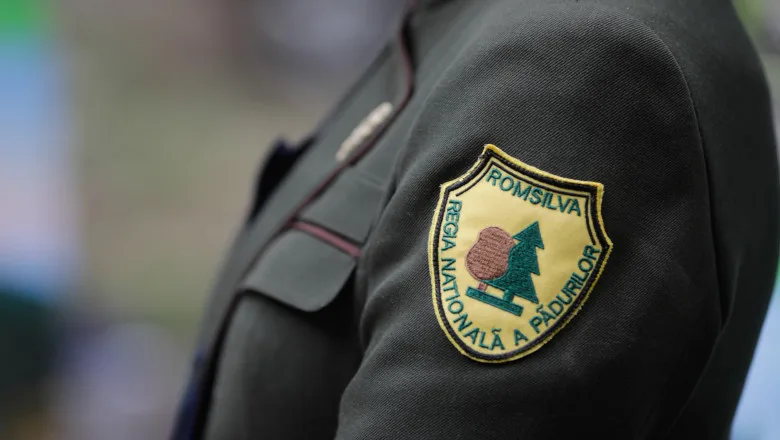 Logo-ul Romsilva pe uniforma unui angajat, simbolizând gestionarea pădurilor.