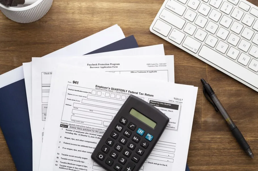 Documente fiscale și un calculator pe un birou de lucru.