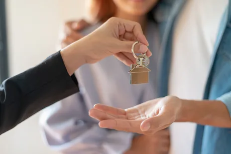 Cumpărător primind cheile unei locuințe, simbolizând finalizarea tranzacției imobiliare.