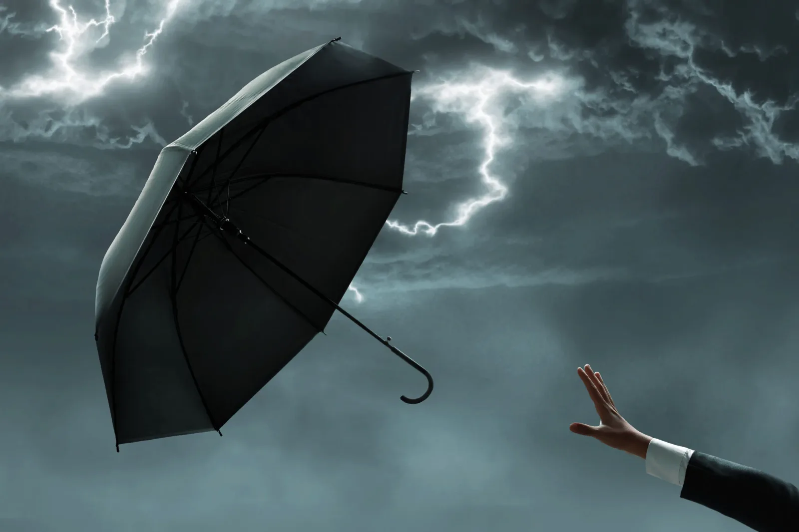 Cer întunecat cu fulgere și un umbrelă întoarsă în vânt puternic.