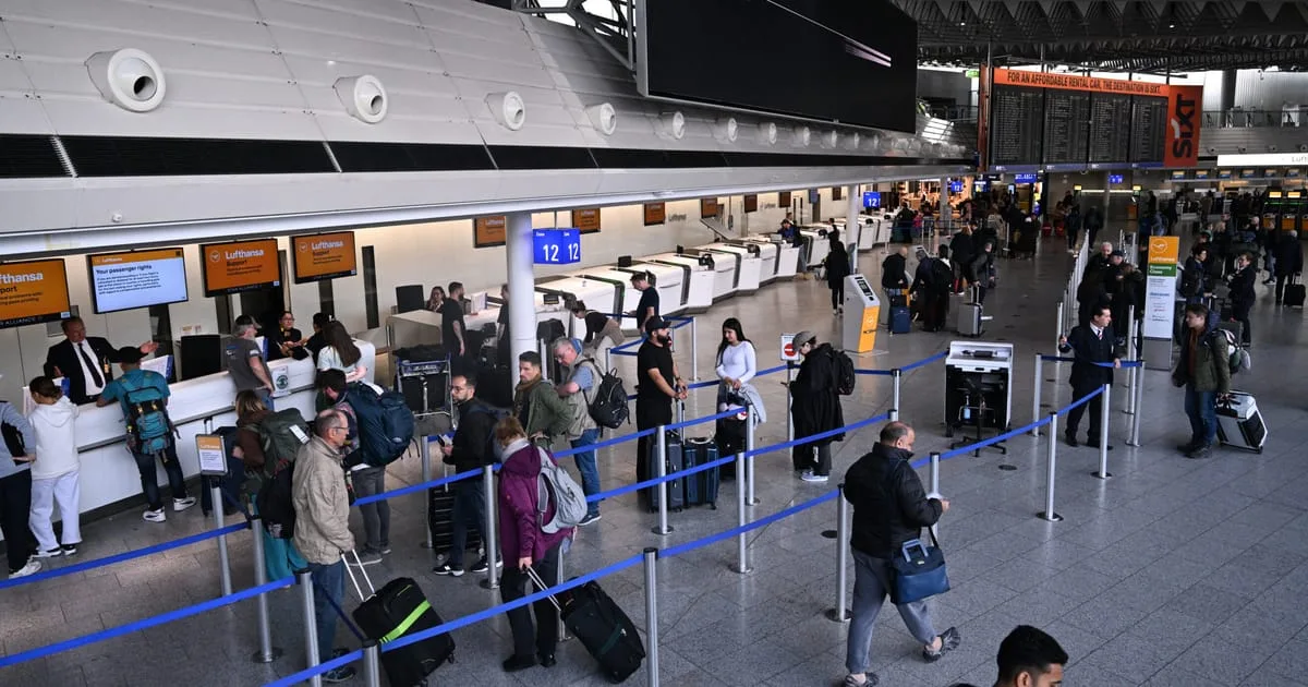 Pasageri așteptând la ghișeul de check-in într-un aeroport aglomerat.