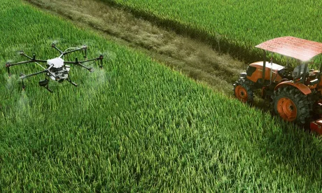Drone și tractor pe câmpuri verzi, simbolizând investiții în agricultură.