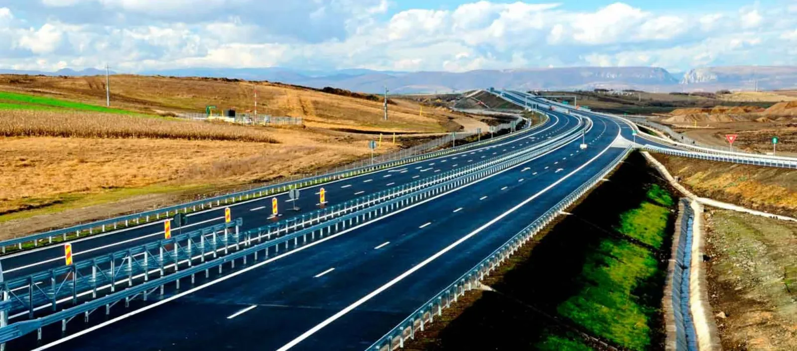 Autostradă cu trafic redus și peisaj montan în fundal.